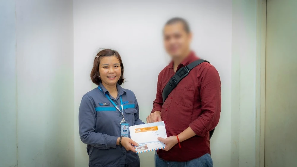 Chị Hà Thị Tươi, nhân viên Đội xe đẩy, Trung tâm Khai thác ga sân bay Nội Bài trả lại tiền cho khách. Ảnh: N.LONG