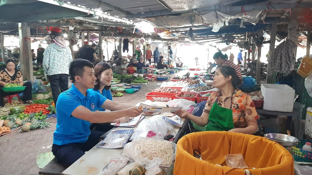 Nhân viên BHXH tuyên truyền các chủ hộ kinh doanh nhỏ lẻ tham gia BHXH tự nguyện. Ảnh: N.LONG