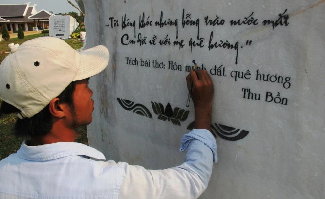 Công nhân tiến hành sửa chữa lỗi chính tả trên tảng đá khắc bài hát “Người mẹ Quảng Nam”chiều 14-3 - Ảnh: TRƯỜNG TRUNG