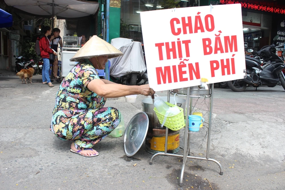 Cô Từ Bình (64 tuổi, quận 10) là khách quen của “Cháo thịt bằm miễn phí”. Khi lấy suất cháo cho mình, cô Bình luôn nhớ chuẩn bị thêm 2-3 phần cho những cụ già khác trong xóm. Thay vì dùng hộp nhựa ở đây, cô thường tự mang hộp nhựa đến để đựng cháo, coi như cách tiết kiệm và trả ơn cô Linh vậy.