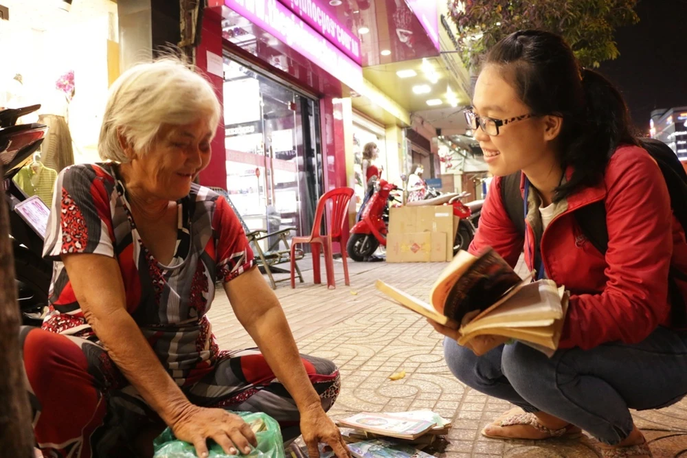 Chùm ảnh: Bà Trình “ghiền” sách cũ ảnh 7 Bà Trình vui vẻ giới thiệu nội dung của từng cuốn sách với khách hàng. Bạn Yến Nhi (sinh viên trường Đại Học Nguyễn Tất Thành) lần đầu mua sách bà Trình cho biết: “Em đang đi bộ trên đường, tình cờ gặp bà đang cầm cuốn sách cũ đọc say mê. Điều đặc biệt ở đây, trời đã tối, chỉ còn đèn đường mờ, nhưng bà vẫn đọc bình thường. Em thấy lạ nên tấp vào hỏi thăm mới biết bà bán sách cũ, nên em chọn mấy cuốn hay mua ủng hộ bà".