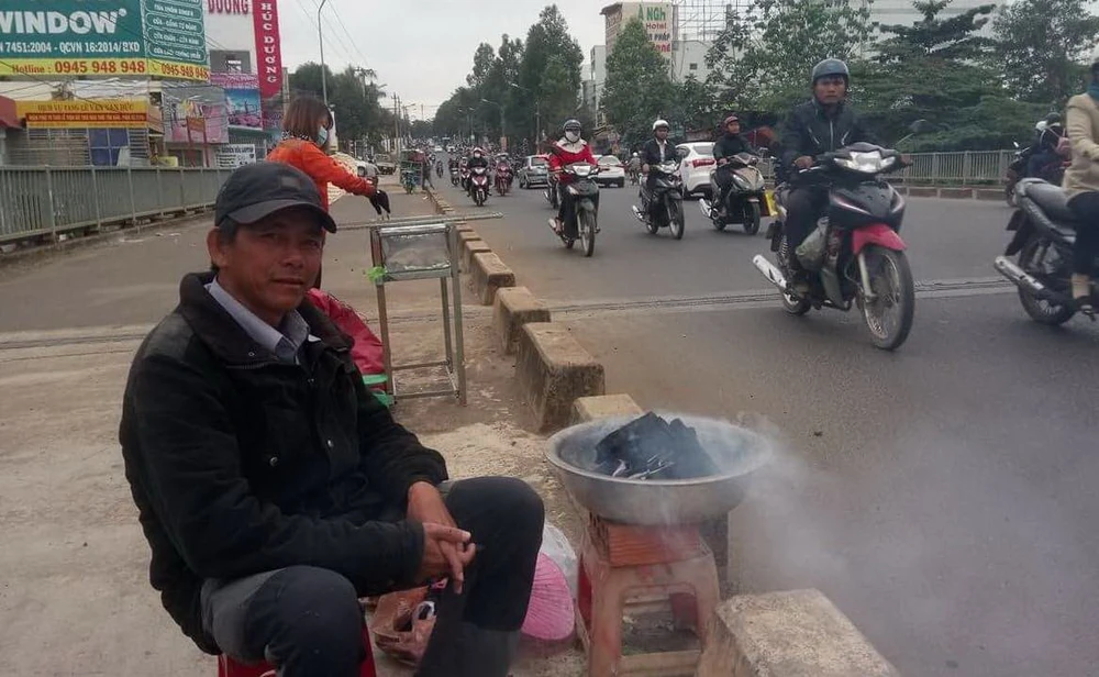 Một người dân ở TP Buôn Ma Thuột đốt than sưởi ấm bên đường.