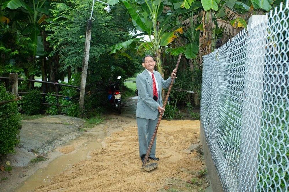 Ông ngoại cô dâu tranh thủ lấp đất vào hố nước trước cổng nhà. Ảnh: NVCC