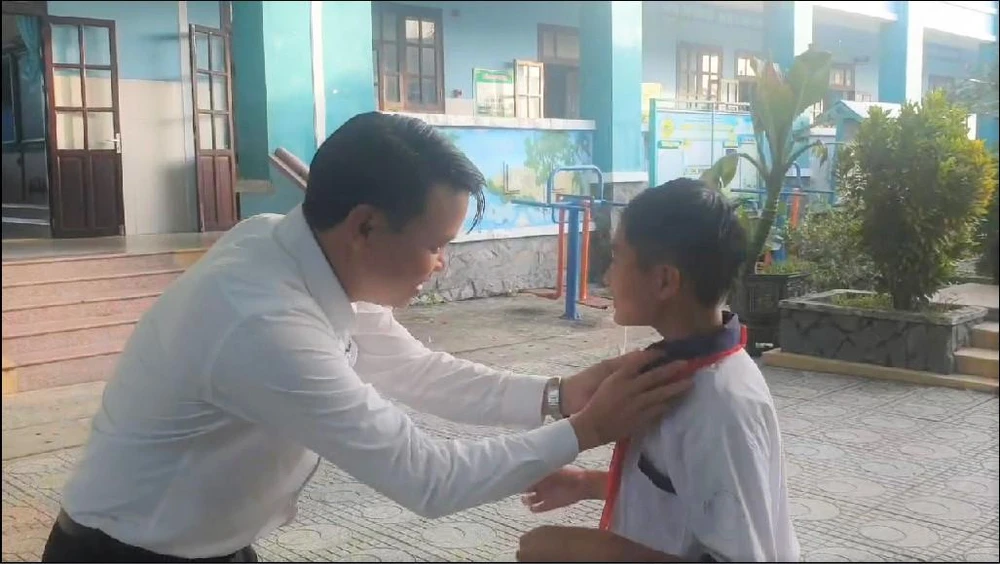 Thầy Bình ân cần chỉnh sửa trang phục cho cậu học trò sau khi cắt tóc xong.