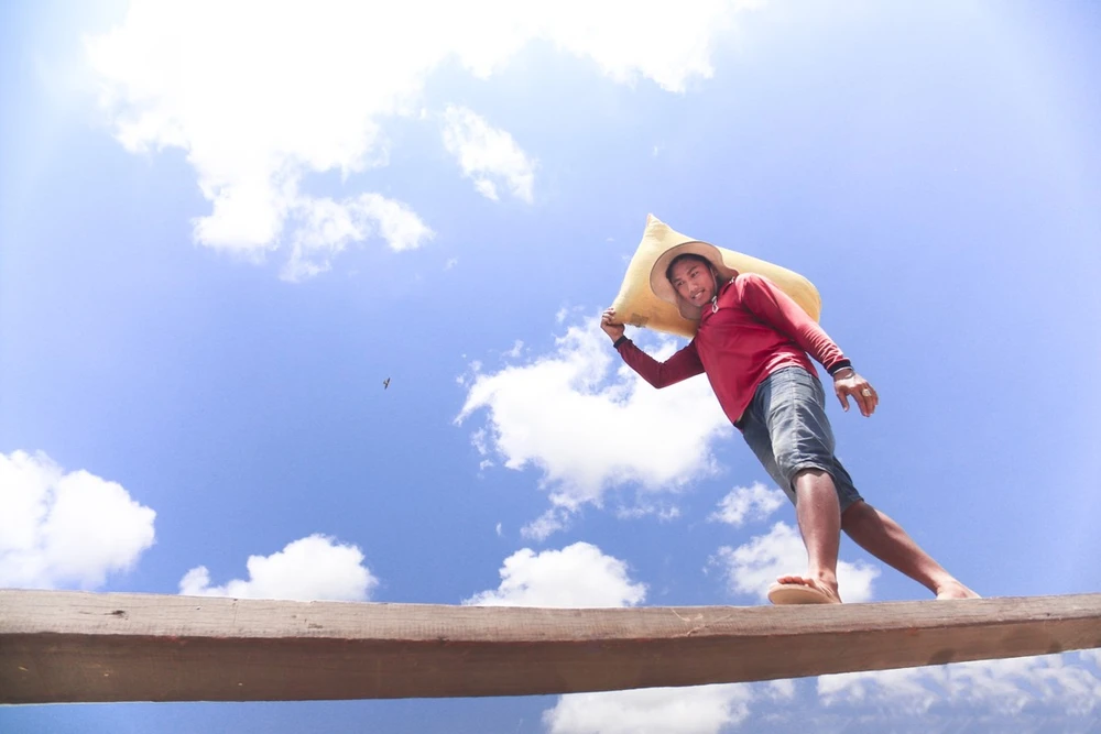 “Giờ này vẫn chưa ăn cơm là chuyện thường. Làm nghề này giờ giấc thất thường lắm, cứ vác hết chủ này lại đến chủ khác, chuyển chủ thì tranh thủ ăn uống lấy sức làm tiếp,có lúa thì vác, chứ không giành giật nhau. Yếu hay mạnh gì cũng vác bằng nhau cả, sau khi mỗi bao lúa được cân xong thì chúng tôi thay phiên nhau vác”- anh Nguyễn Văn Thanh, trưởng nhóm nói sau khi đỡ bao lúa lên vai đồng nghiệp.