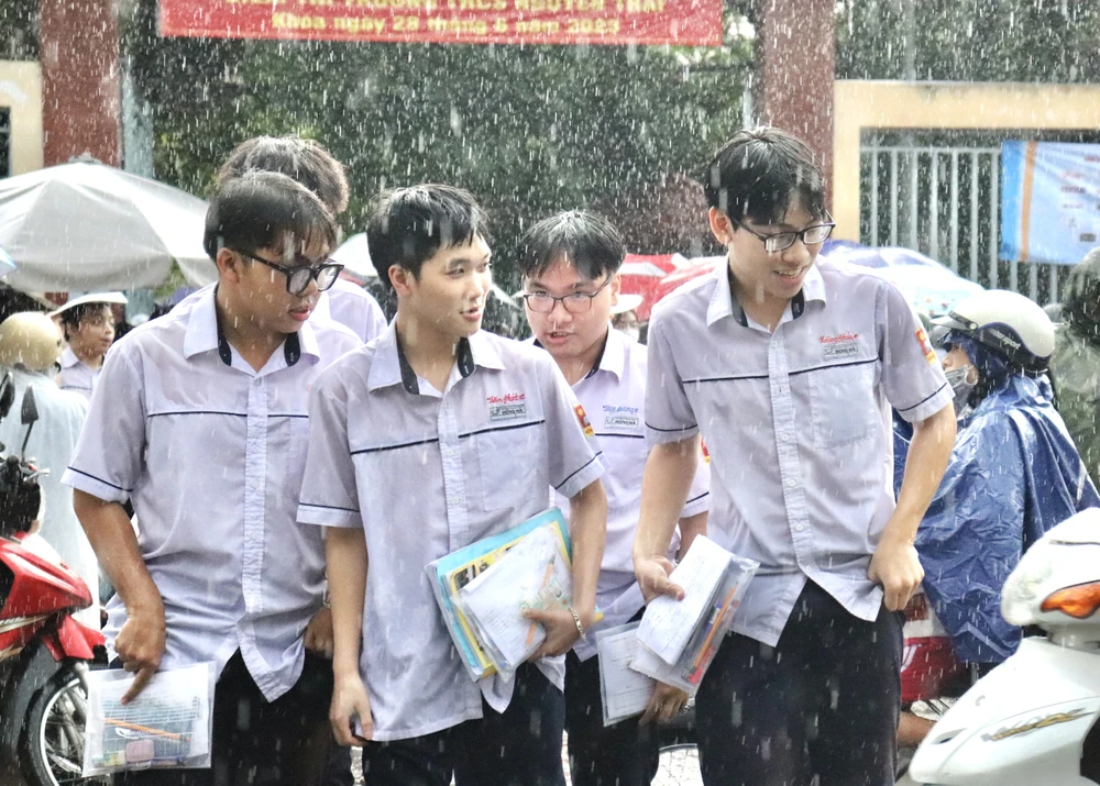 Thí sinh rời phòng thi trong cơn mưa lớn chiều qua tại TP.HCM. Ảnh: Di Linh