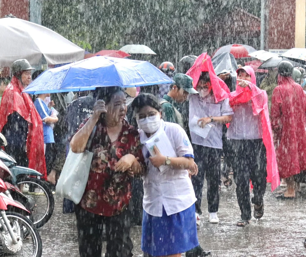 Bước ra khỏi phòng thi, trời đổ mưa lớn, đã có mẹ ở bên ngoài chở che. Ảnh: Di Linh