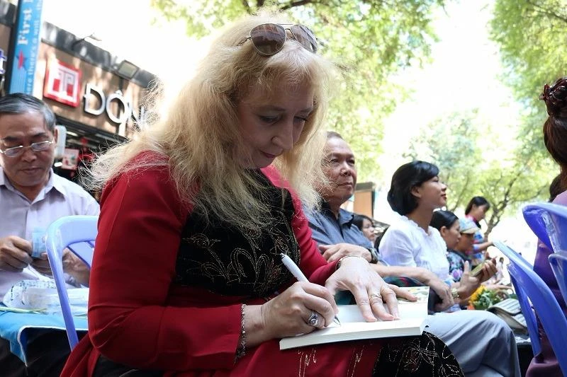 Bà Elena trong tà áo dài, ký tặng sách cho mọi người. 