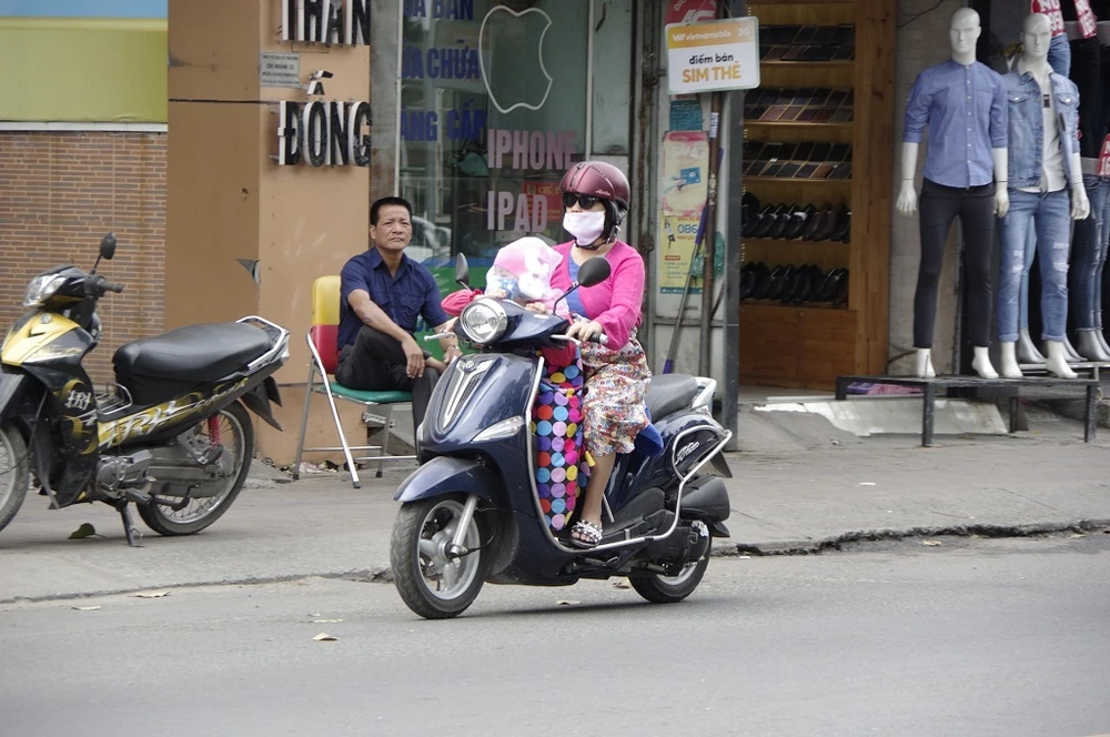 Một em bé được mẹ trùm kín từ đầu tới chân để tránh gió lạnh.