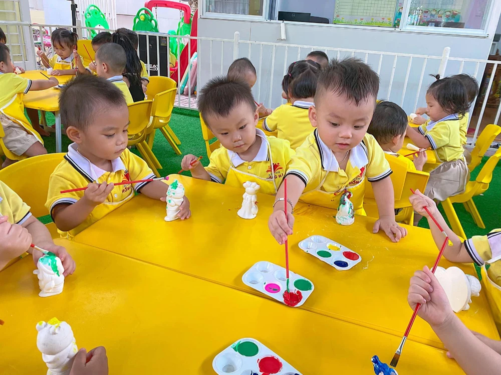 Các em nhỏ được hướng dẫn cách tô tượng. Ảnh: Hồng Quỳnh