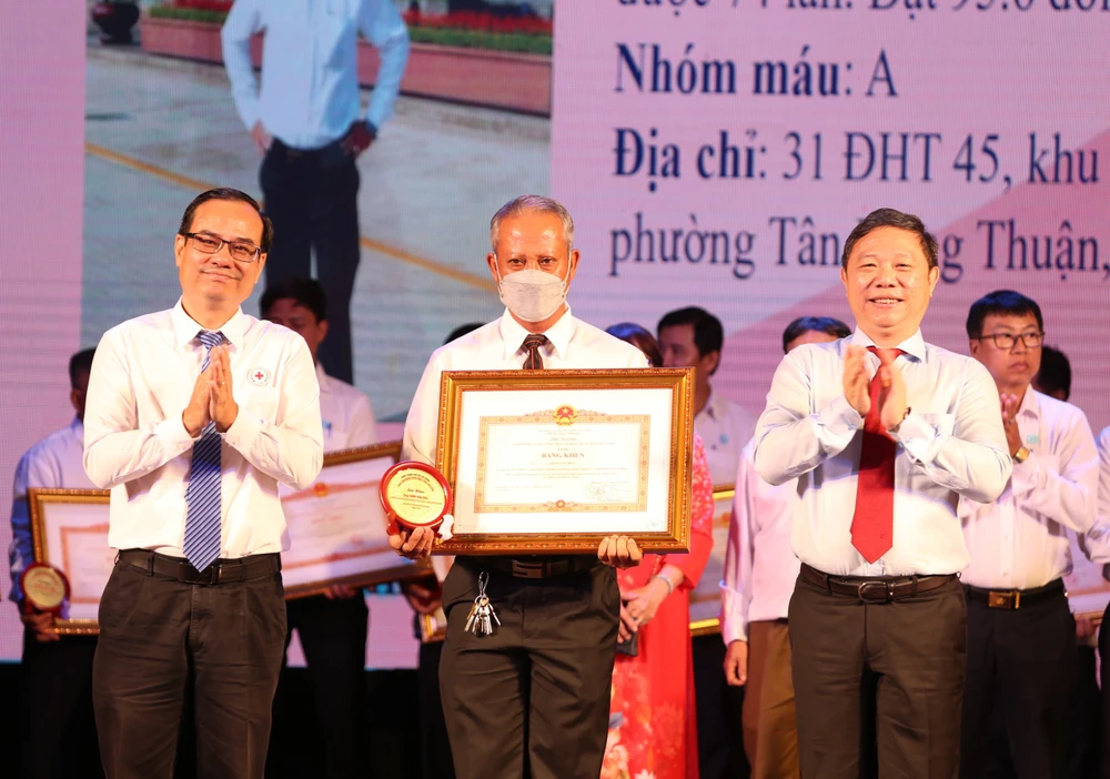 Ông Dương Anh Đức (phải) trao bằng khen của Thủ tướng Chính phủ cho cá nhân có thành tích trong phong trào hiến máu. Ảnh: THẢO PHƯƠNG