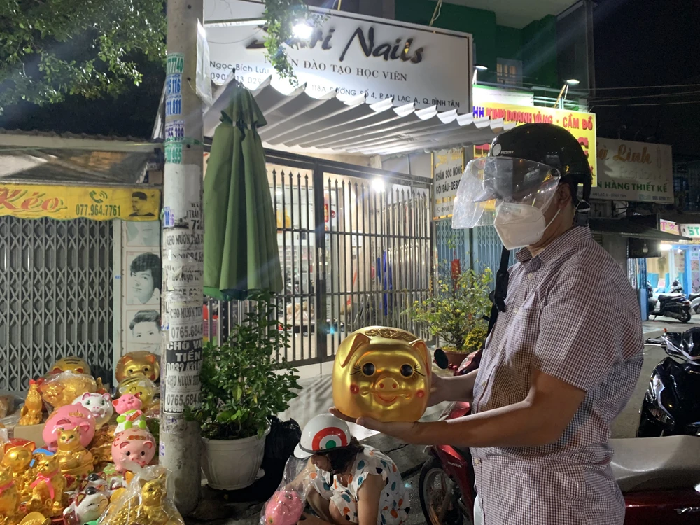 Cầm con heo vàng rực được người bán giới thiệu là heo kim tiền, tượng trưng cho lộc đầu năm, anh Lê Văn Vẻ (40 tuổi, ngụ phường 13, quận 6) cho biết, gia đình anh cứ mỗi mùng 10 tháng giêng sẽ mua heo để các con bỏ ống tiết kiệm cho cả năm. Ảnh: THẢO PHƯƠNG