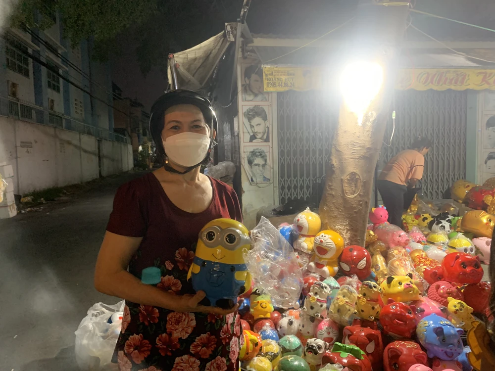 Vô tình đi ngang thấy mọi người dừng lại mua heo đất, bà Tuyết (64 tuổi, ngụ phường An Lạc A, Bình Tân) cũng ghé vào mua heo đất cho các cháu ở nhà. Ảnh: THẢO PHƯƠNG