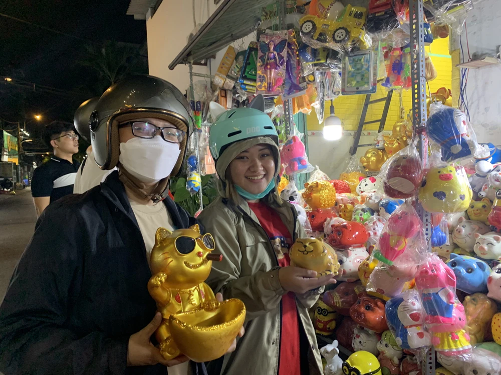 Sau một hồi chọn lựa thật kĩ, chị Nguyễn Ánh Ngọc (27 tuổi, ngụ quận 11) đã quyết định mua chú mèo thần tài để gửi gắm may mắn tiết kiệm. Chú mèo đeo kính hút thuốc này được người bán giới thiệu “giữ tiền là không ai lấy được của mình”. Được biết đây là lần đầu chị mua heo đất vào ngày vía Thần Tài. Ảnh: THẢO PHƯƠNG