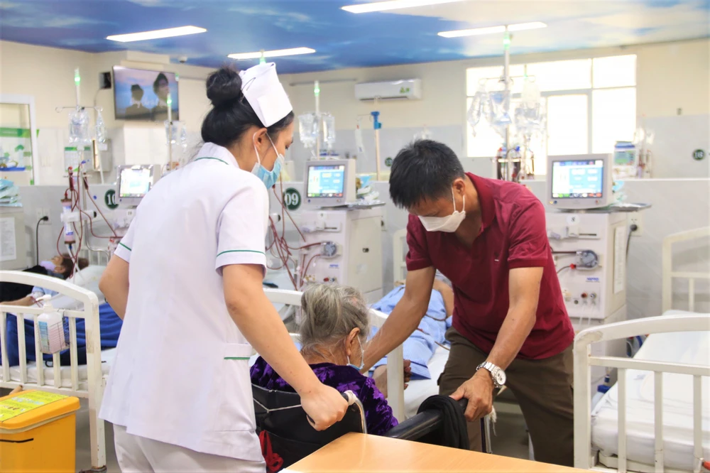 Chị Trinh ân cần đỡ bệnh nhân dậy sau khi đã chạy thận xong. Ảnh: THẢO PHƯƠNG