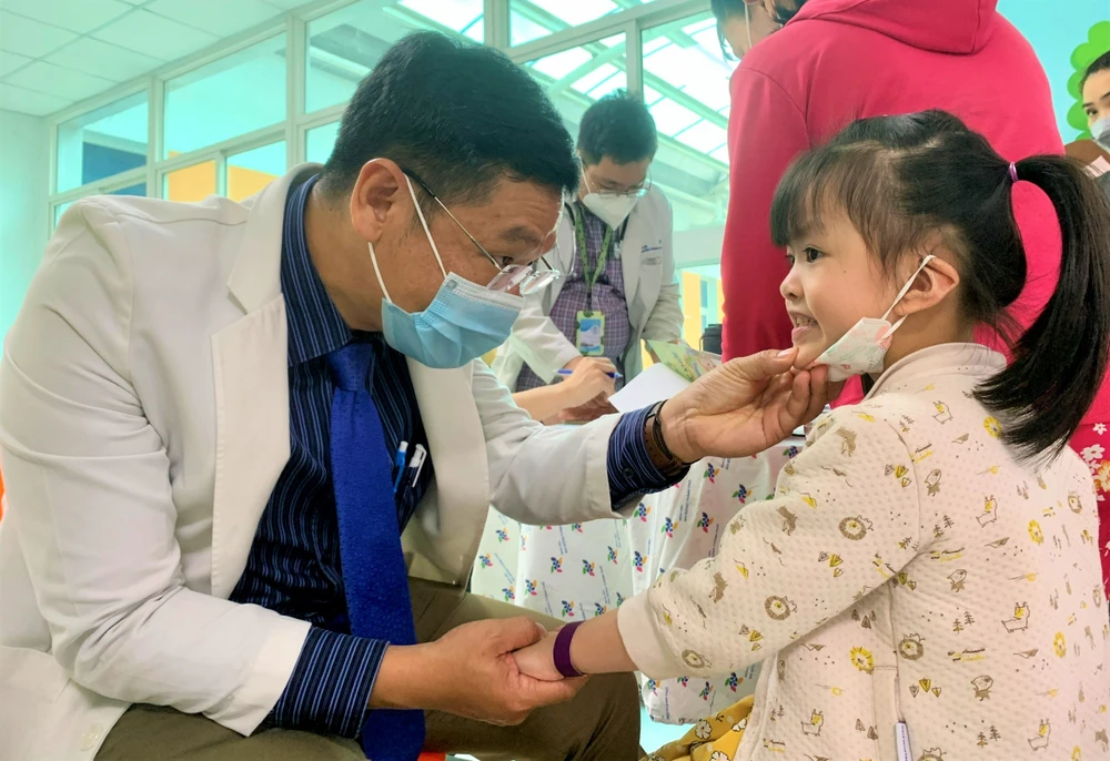 BS Nguyễn Trần Nam kiểm tra răng miệng cho bé gái. Ảnh: THẢO PHƯƠNG