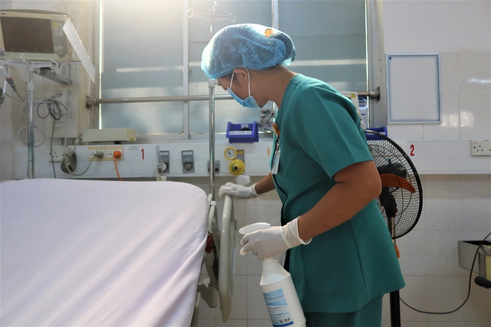 Chị Trang Thị Kim Loan lau dọn từng ngóc ngách giường bệnh. Ảnh: THẢO PHƯƠNG