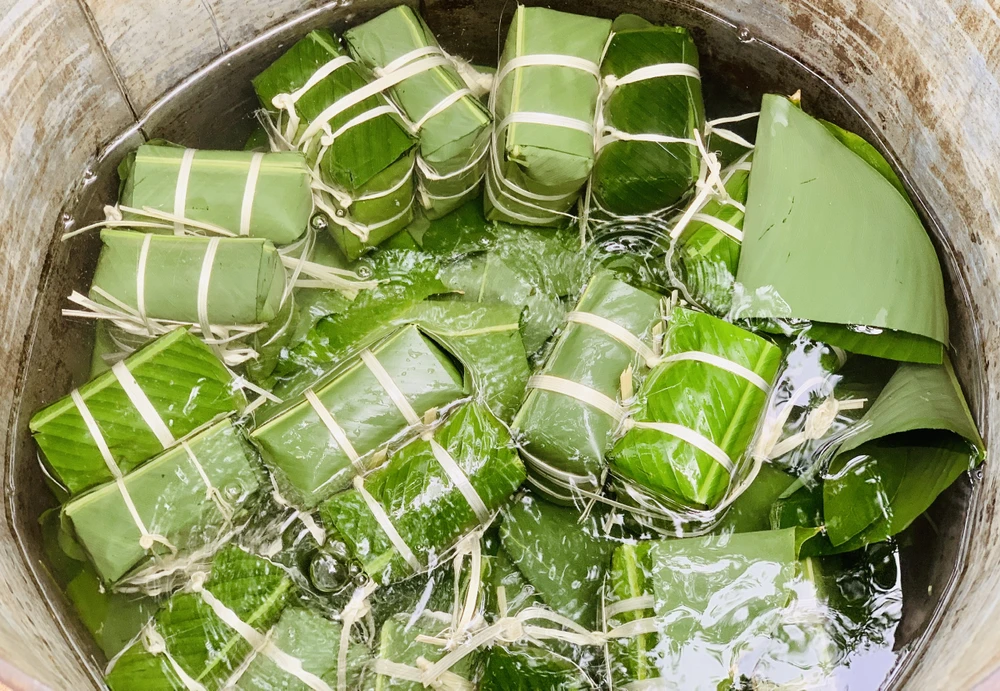 Gói bánh quan trọng khâu cuốn lá hình tam giác, gói vuông vức bốn góc là bánh sẽ đẹp. Ảnh: THẢO PHƯƠNG
