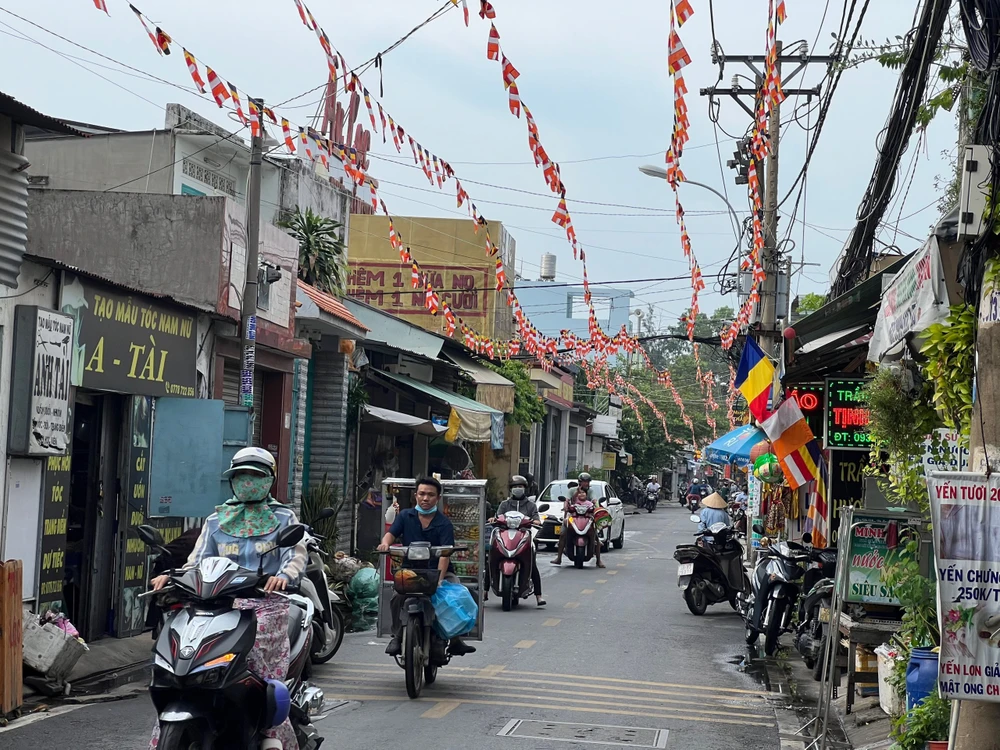 Cờ Phật giáo được treo khắp nơi trên đường dẫn vào chùa Hoằng Pháp (quận Hóc Môn, TP.HCM). Lá cờ thường gồm 5 sắc: Xanh, vàng, đỏ, trắng, và vàng cam là tượng trưng năm đạo hào quang của Đức Phật. Ảnh: QUỐC HƯƠNG.