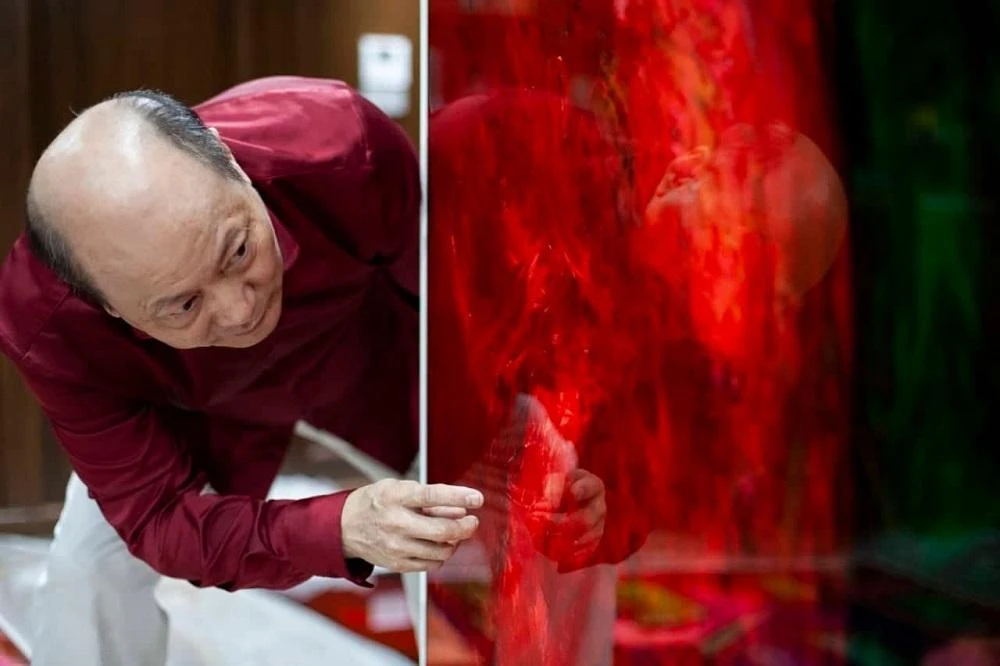 Họa sĩ Ngô Xuân Bính bên một tác phẩm của mình.