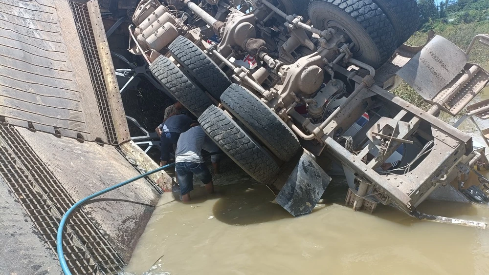 Cơ quan chức năng và người dân đang hút bê tông tươi ra khỏi bồn để kéo xe lên