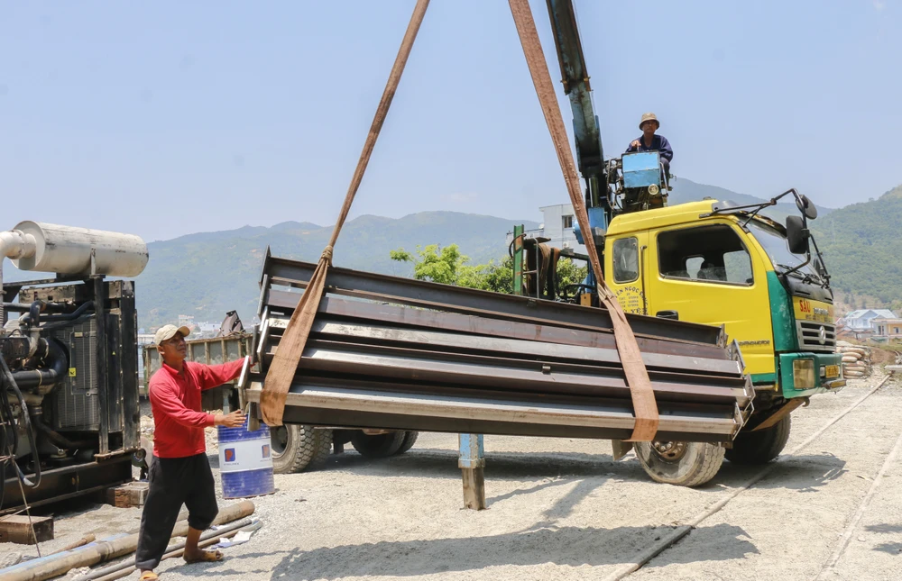 Công nhân vận chuyển sắt thép đến cửa hầm phục vụ gia cố để phun vữa bê tông.