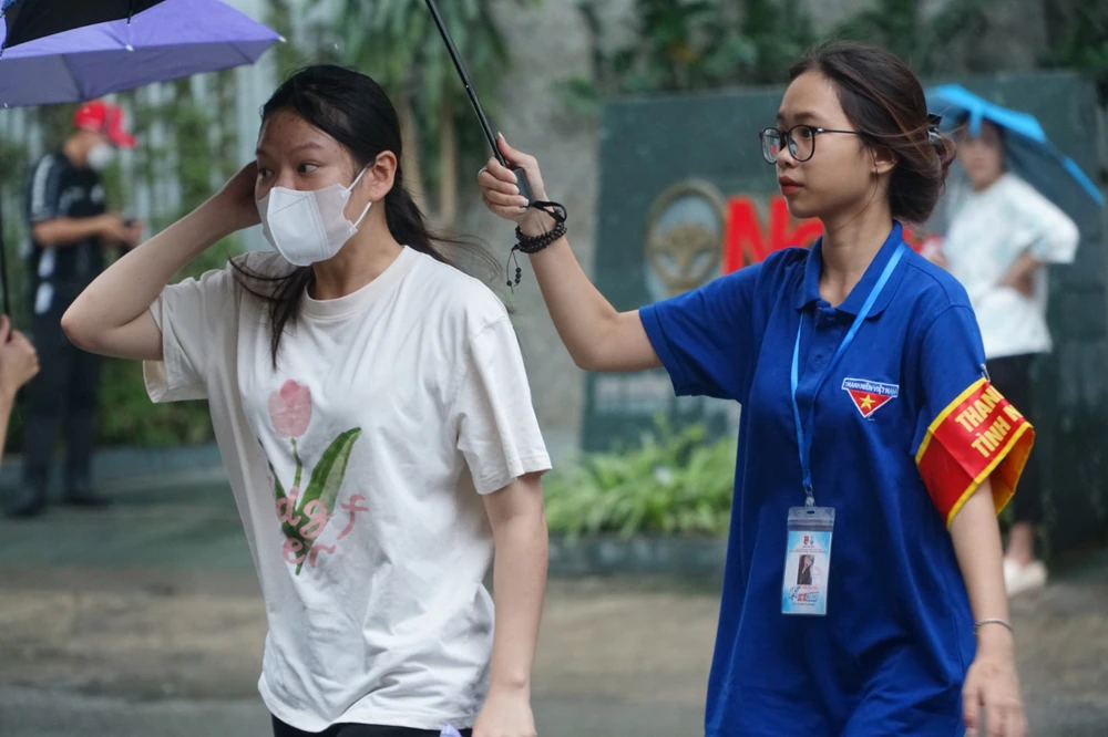 Thí sinh được sinh viên tình nguyện che dù đưa vào điểm thi. Ảnh: Phi Hùng