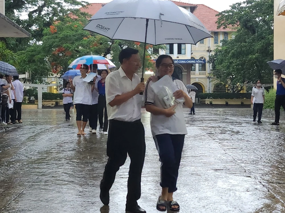 Thí sinh thi xong môn Toán ra về trong cơn mưa chiều. Ảnh: NGUYỄN QUYÊN