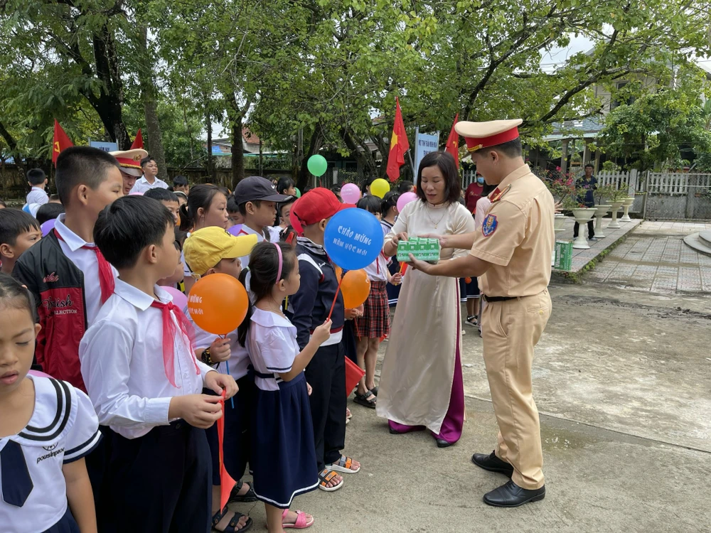 Chiến sĩ Trạm CSGT Phú Lộc, Phòng CSGT tỉnh Thừa Thiên Huế tặng sữa cho các em học sinh trong ngày khai giảng. Ảnh: NGUYỄN DO