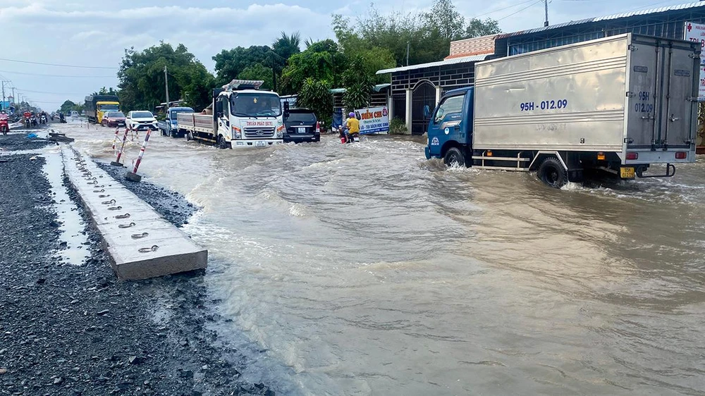 Tình trạng ngập nhiều đoạn trên Quốc lộ làm lưu thông của người và phương tiện rất khó khăn. Ảnh: PHẠM TRINH
