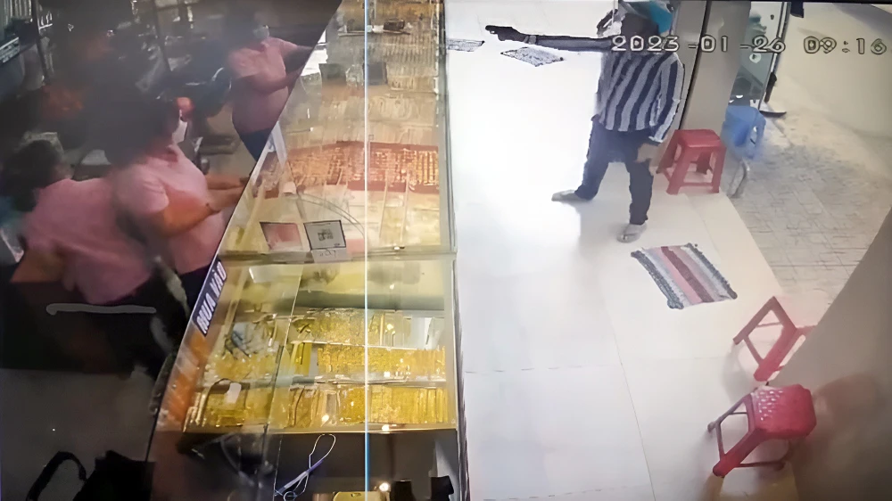 Bị can Tăng Minh Phúc (áo sọc) lấy ra một vật giống súng đe dọa nhân viên tiệm vàng TT ở TP Sóc Trăng nhằm cướp tài sản. Ảnh: DIỄM HẰNG