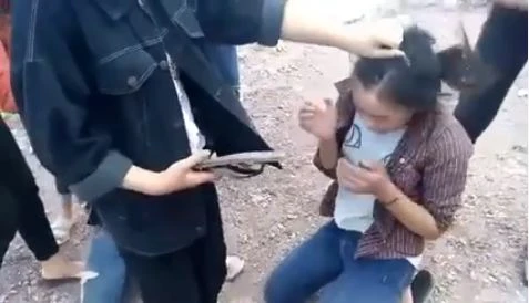 Một nữ sinh túm tóc và dùng dép đánh vào người nữ sinh khác. Ảnh cắt từ video clip