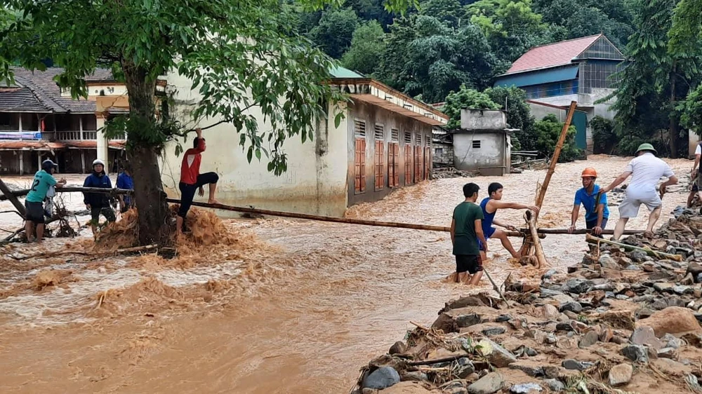 Lực lượng chức năng làm cầu khỉ vượt nước lũ để vào tiếp cận bản Sơn Hà, xã Tà Cạ.