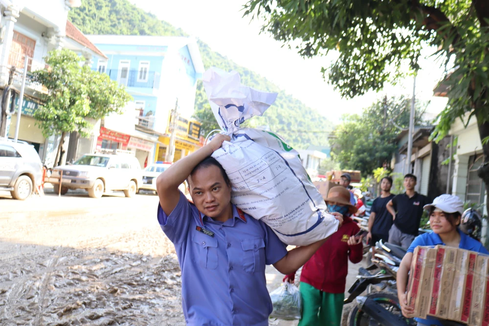 Cán bộ VKSND huyện Kỳ Sơn mang đồ dùng vào giúp dân.
