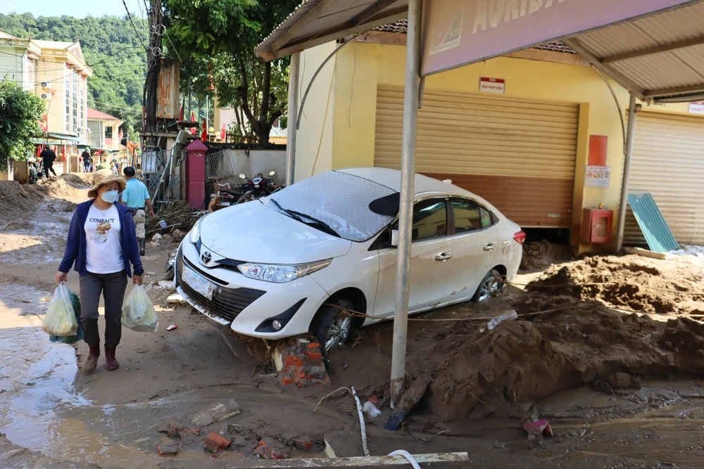 Ngổn ngang bùn, đất và những chiếc xe hơi của người dân bị lũ cuốn chưa thể mang đi sửa chữa.