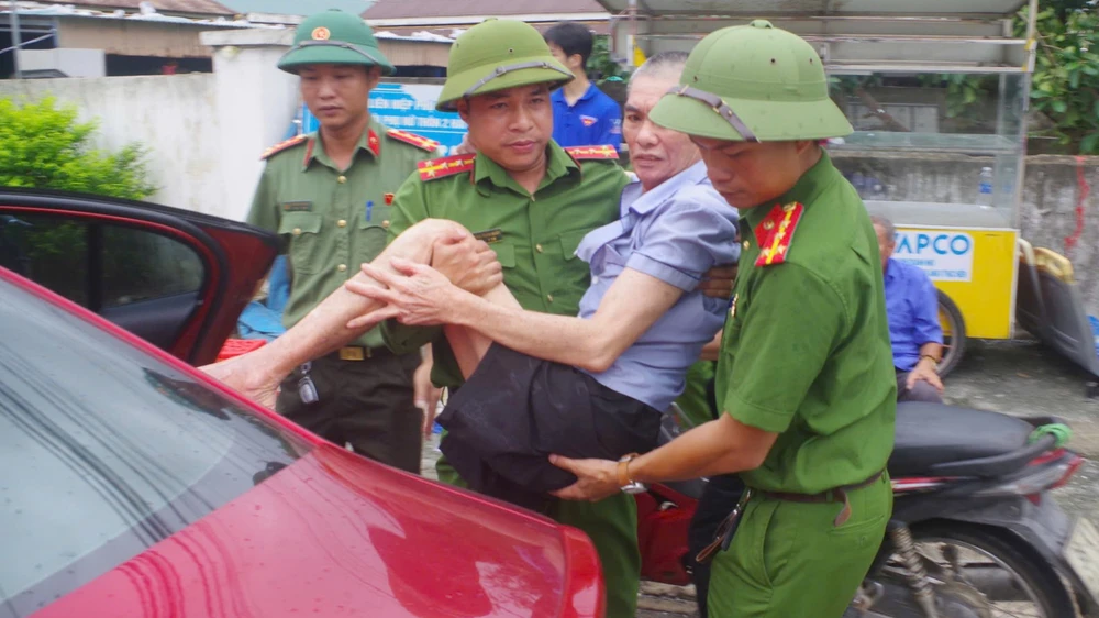 Cán bộ công an bế người dân ở phường Sông Trí lên xe hơi và di chuyển đến nơi cao trú ẩn.