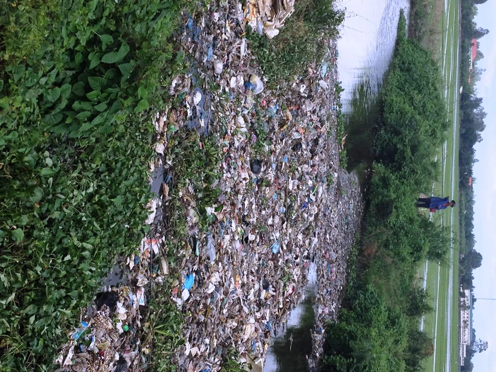 Nước kênh đen ngòm và đầy rác thải nên nông dân không dám lấy nước vào ruộng(ảnh KHÁNH HOÀNG)