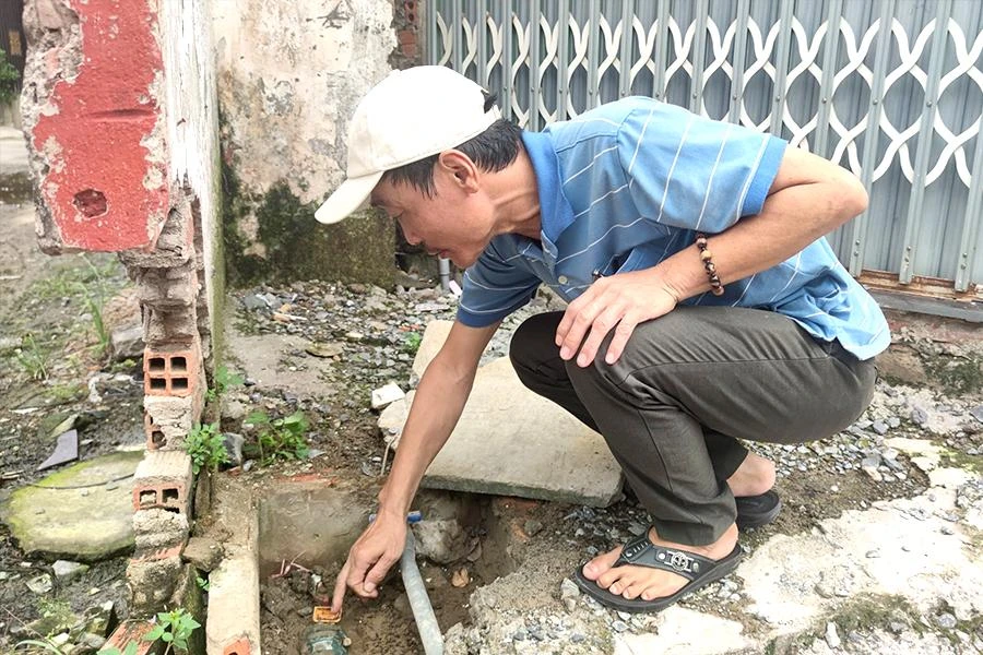 Ông Rau đang xem lại đồng hồ nước nhà mình và không hiểu vì sao tiền nước tháng 9 lại tăng nhiều đến thế. Ảnh: NGUYỄN HIỀN