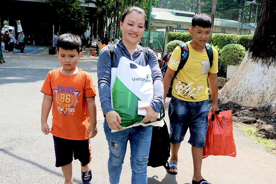 Chị Lê Thị Loan (33 tuổi, quê Quảng Ngãi) cùng các con hạnh phúc bước lên “chuyến xe yêu thương” về quê đón tết do Liên đoàn Lao động TP.HCM tổ chức. Ảnh: TÚ NGÂN