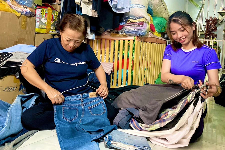 Mỗi buổi chiều, chị Nguyễn Thị Ngọc Trâm (phải) đều cẩn thận phân loại quần áo cũ của mọi người từ khắp nơi mang đến tặng. Ảnh: TÚ NGÂN