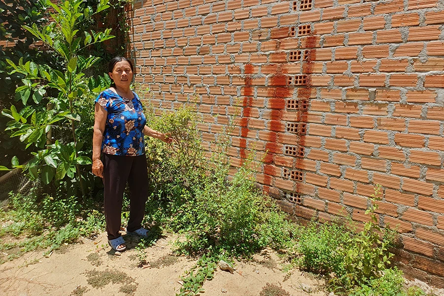 Bà Nông chỉ vết sơn đỏ, cho rằng đây là vị trí đường đi cũ đã bị ông H lấn chiếm để xây nhà. Ảnh: QN