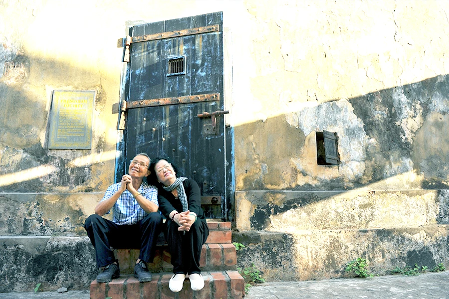 Vợ chồng tử tù Võ Văn Em và cựu tù Đặng Thị Nga đang ngồi trước phòng giam đặc biệt, nơi đã giam giữ tù nhân lao động khổ sai (hầm xay lúa). Ảnh: NGUYỄN Á