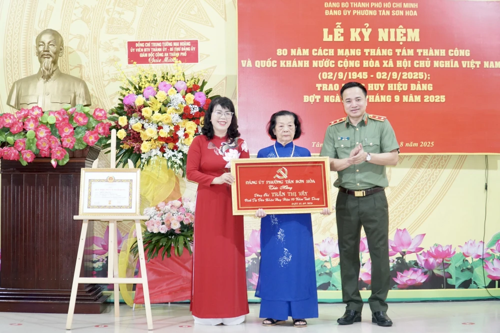 Trung tướng Mai Hoàng và bà Trương Lê Mỹ Ngọc, Bí thư Đảng uỷ phường Tân Sơn Hoà, trao khánh vàng và Huy hiệu 70 năm tuổi Đảng cho đảng viên. Ảnh: BẢO PHƯƠNG