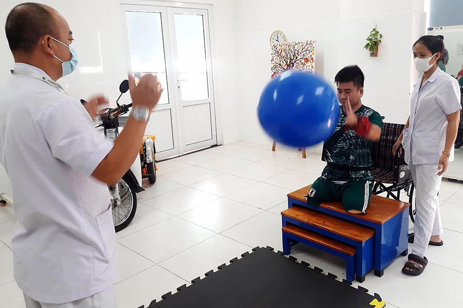 Kỹ thuật viên hướng dẫn Đại úy Ngôi quăng quả bóng to để tập căng cơ tay.jpg