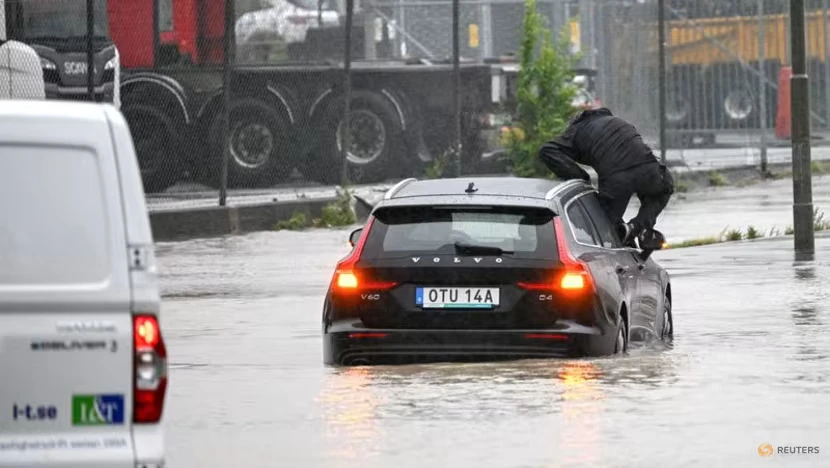 Người dân leo lên nóc ô tô để tránh lũ tại Thụy Điển hôm 7-8. Ảnh: REUTERS