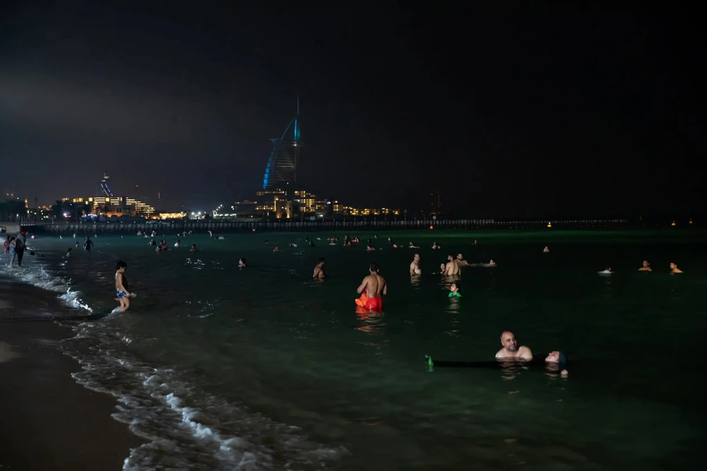 Du khách tại một bãi biển đêm ở Dubai (Các Tiểu vương quốc Ả Rập Thống nhất). Ảnh: THE NEW YORK TIMES