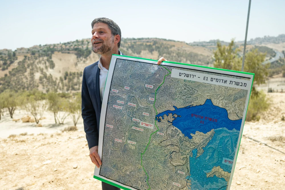 Bộ trưởng Tài chính Israel Bezalel Smotrich cầm bản đồ dự án định cư E1 (màu xanh đậm) tại cuộc họp báo ở Ma’ale Adumim, ngày 14-8. Ảnh: Yonatan Sindel/Flash90