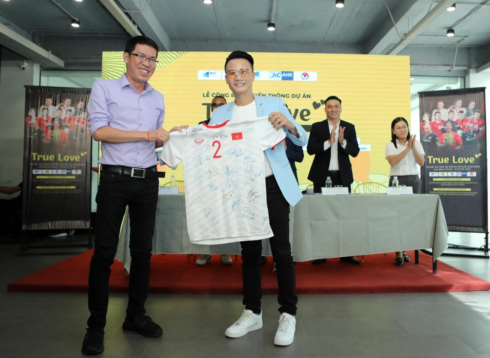 Nhà báo Đỗ Tuấn (báo Bóng đá) trao tặng chiếc áo đấu của trung vệ Duy Mạnh cho ca sỹ Hoàng Bách bán đấu giá trong chiến dịch True Love...