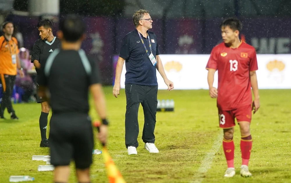 HLV Troussier đội mưa chỉ đạo học trò và hài lòng với chiến thắng Malaysia để sớm vào bán kết, sau những áp lực từ 5 trận thua trước SEA Games 32. Ảnh: ANH PHƯƠNG.