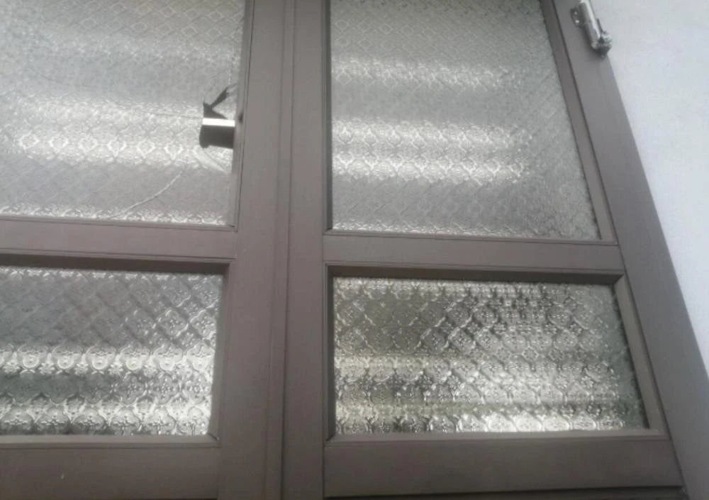 Cửa nhà ông Phúc bị bắn vỡ kính, rất may không có ai bị thơpng. Ảnh MINH KHANG